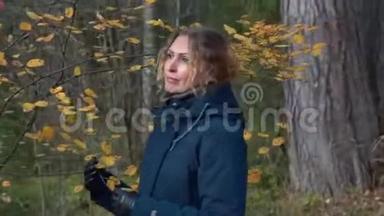 一个苗条<strong>甜美</strong>的女人走过一片美丽的秋天森林，在桦树和枞树之间，欣赏着枯<strong>黄</strong>的叶子